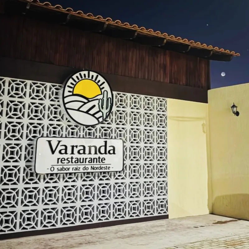 Fachada do restaurante à noite, vista de longe, com o telhado de barro