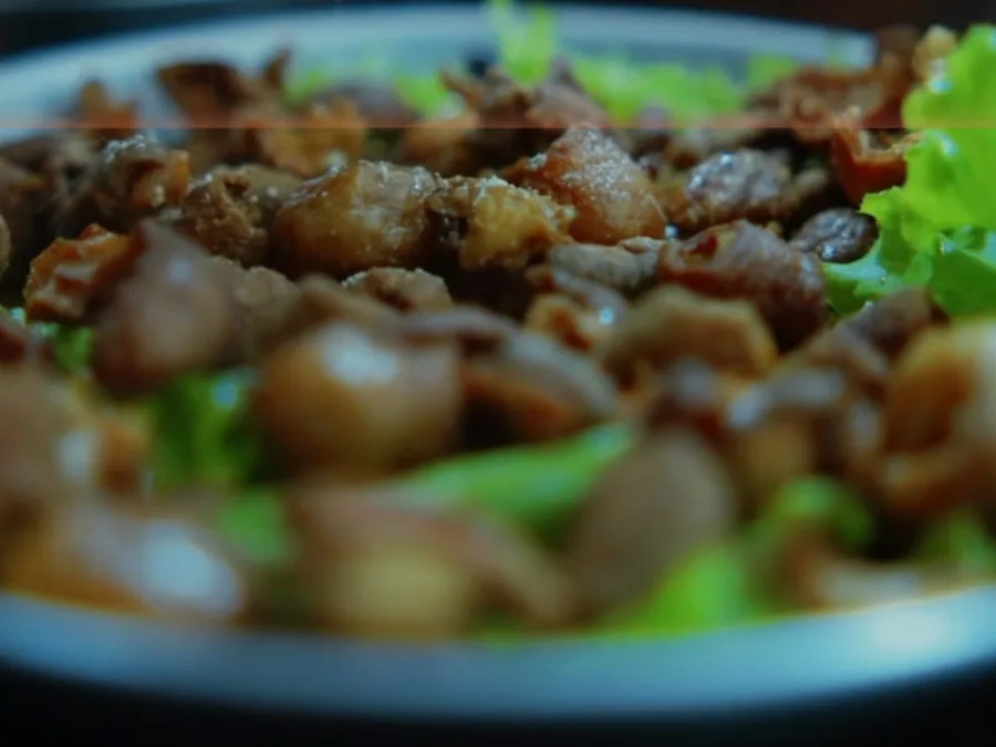 Tigela com carne desfiada e folhas verdes, vista de perto